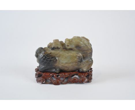 A Chinese black and grey jade carving of a reclining kylin Ming style 19th Century with turned over its back and spewing fort