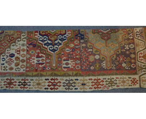 A Kelim half runner with a central panel of purple ground, with a white border including symbols 
