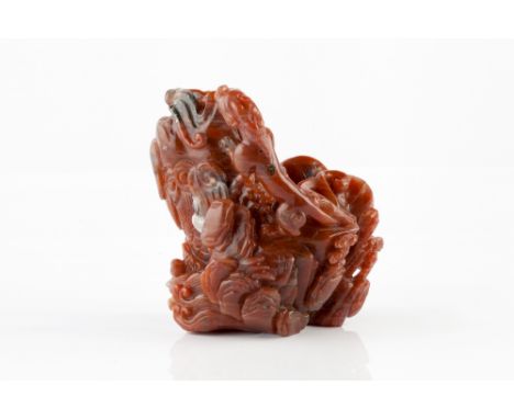 A Chinese red agate boulder late 19th Century with grey green and crystal-like inclusions and carved as a dragon fish vase le