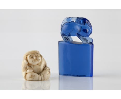 A Chinese blue Peking glass seal 19th Century 5cm and a Japanese netsuke in the form of Daikoku, Meiji period (2)