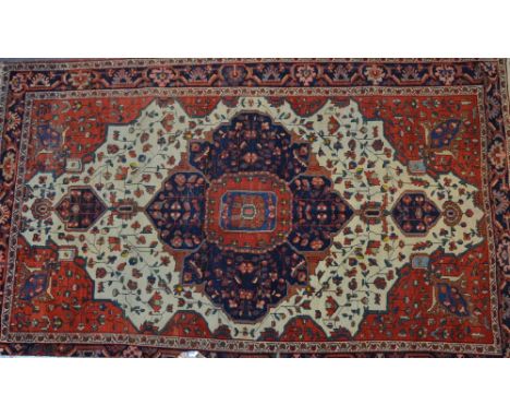 A Sarouk Rug of red and white ground, displaying a central panel as a leaf, with a border displaying medallions, 210cm long x