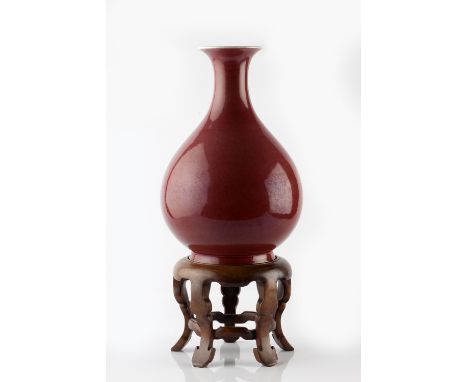 A Chinese pear shaped bottle vase 18th Century decorated with a peach bloom glaze, on wood five footed stand, 30.5cm high