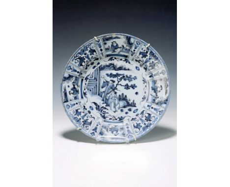 Großer Teller nach Kangxi-Vorbild, wohl Hanau, 1.H.18.Jh.,  unterglasurblauer Dekor, figürliche Szene in Gartenlandschaft, Fa