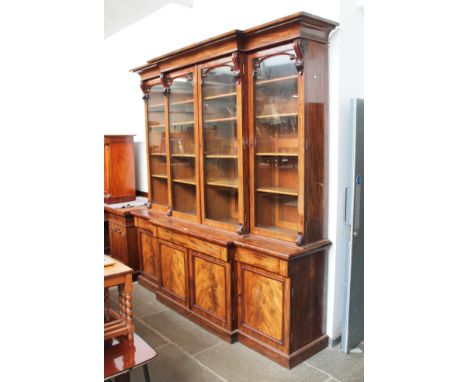 A Victorian mahogany breakfront bookcase, circa 1860, with cornice top, scroll supports and moulded detail to glazed doors, t