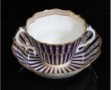 A Worcester porcelain chocolate cup and saucer, circa 1770, of scalloped form and decorated in blue and gilt stripes with fur