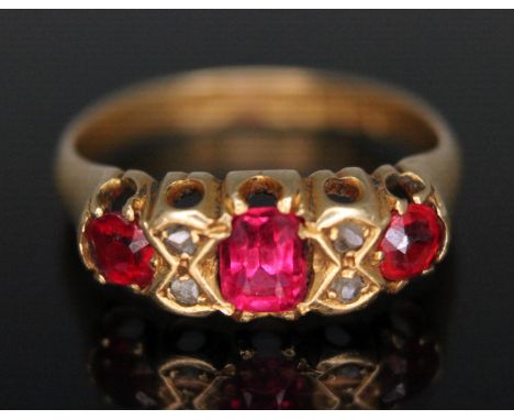 An Edwardian 18ct gold cluster ring set with a central garnet topped doublet, paste either side and four small diamonds, spon