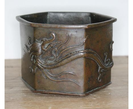 A Chinese bronze censor, 19th century, hexagonal form with mythical dragon in relief, stood on three feet, bearing six charac