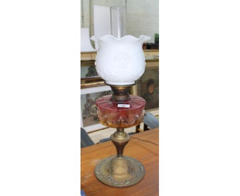 An Art Nouveau brass and pink glass oil lamp, height 60cm.  There is a slight chip to the clear glass.
