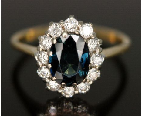 A diamond and sapphire cluster ring, the central oval mixed cut sapphire weighing approx. 1.62 carats, surround by twelve mod