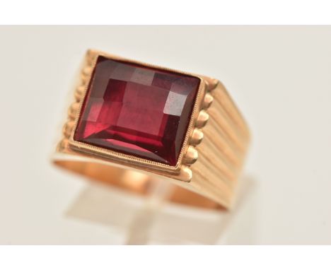 A YELLOW METAL GEM SET RING, a large faceted synthetic ruby, collet set in yellow metal, scalloped detail to the tapering sho