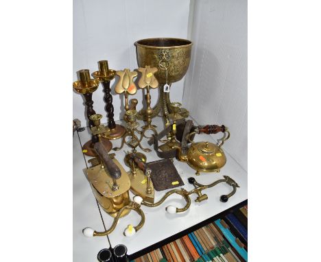 A COLLECTION OF BRASSWARES to include two brass irons, five candle sticks (to include two pairs), a brass kettle, a large bra