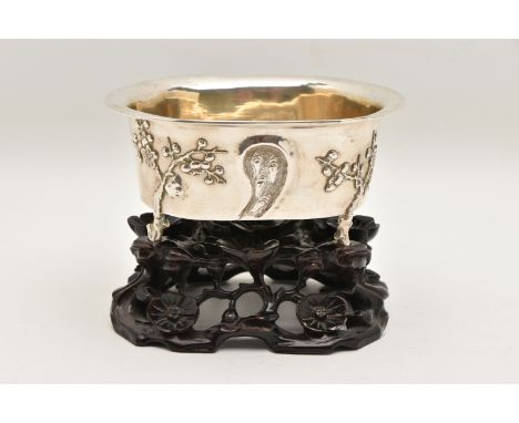 AN EARLY 20TH CENTURY CHINESE SILVER JARDINIERE WITH HARDWOOD BASE, of an oval form, embossed pronus blossom pattern with the