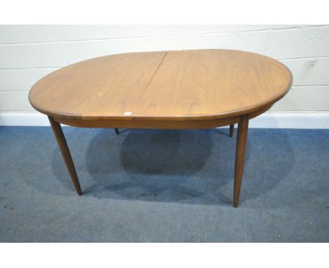 G PLAN, A MID CENTURY TEAK OVAL EXTENDING DINING TABLE, with a single fold out leaf, raised on cylindrical tapered legs,  len