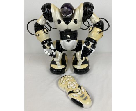 A 2004 Robosapien by Wowee, complete with remote control. Sun damage to both robot and remote. Approx. 33cm tall. 