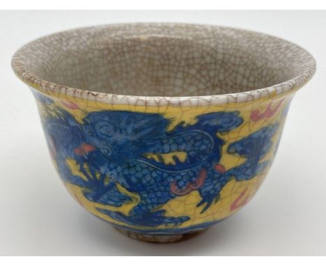 A Chinese crackle glaze ceramic tea bowl. Yellow ground with blue dragon &amp; phoenix design to outer bowl. Signature mark t