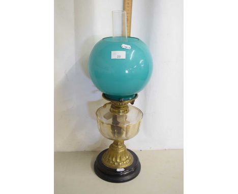 An oil lamp with turquoise shade and clear glass font