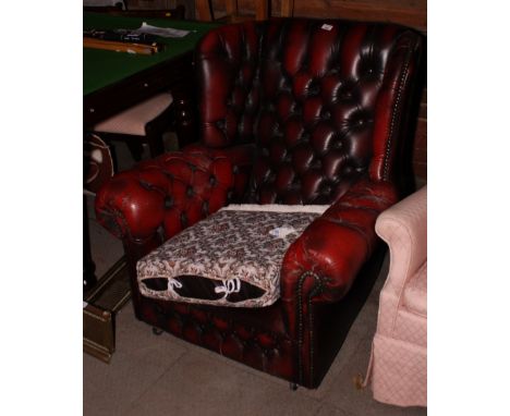 A wing armchair, button upholstered in a crimson leather
