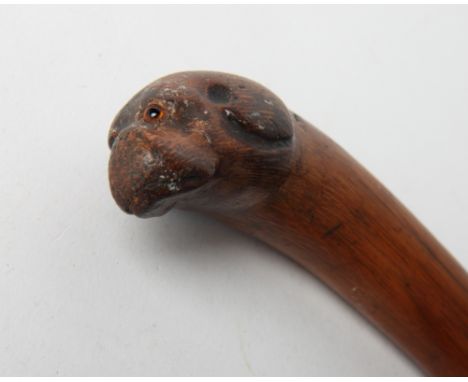 A wooden walking stick with curved handle carved dog's head with red glass eyes