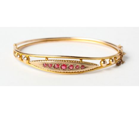 An Edwardian 9ct gold and ruby bangle, 6.4g