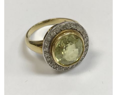 An 18 carat gold set ladies dress ring, the central peridot approx 6 carats, within a band of 23 diamonds, size R