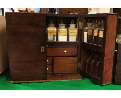 A Victorian mahogany apothecary's cabinet the two doors each fitted with eight bottle compartments containing eight original 