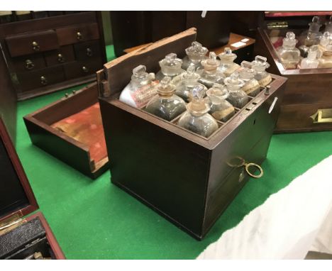 A 19th Century mahogany apothecary's chest, the rising lid opening to reveal twelve bottle compartments and bottles over a fi