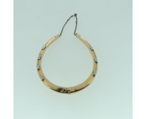 An early 20thC hollow Hinged Bangle, modelled in the form of a horseshoe, with safety chain, unmarked but tested as probably 