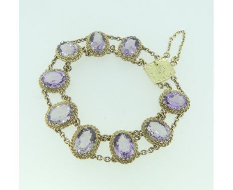 A 9ct yellow gold and amethyst Bracelet, formed of nine oval facetted amethysts mounted in ropetwist borders, with chain link