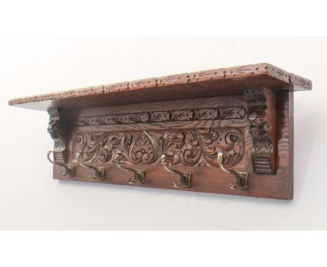 A carved oak coat rack in the 19th century Elizabethan revival style - the floral and foliate carved top shelf on carved lion
