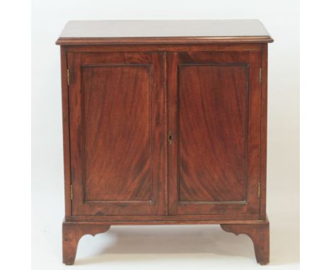 A small Edwardian mahogany cabinet - the moulded top over a pair of panelled doors enclosing a single later shelf, on bracket