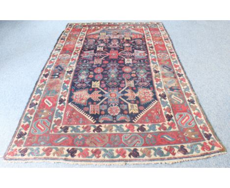 An antique rug - 19th century, with three winged, X-shaped medallions on a dark blue field with all over geometric and floral