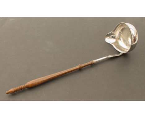 A small 18th century white-metal brandy or toddy ladle - the oval bowl with inset Charles III 1785 coin, with turned wooden h