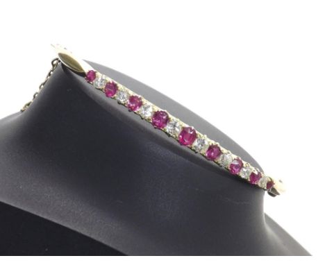 Early 20th century graduated ruby and diamond hinged bangle, with nine graduated round-cut rubies interspersed with eight rou