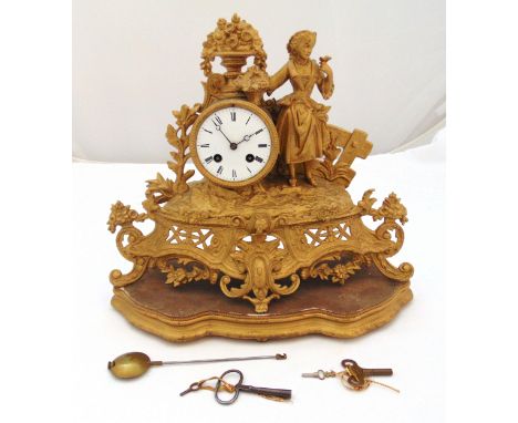 A 19th century gilt metal mantle clock in the form of a maiden holding a basket of flowers in a garden setting, the white ena