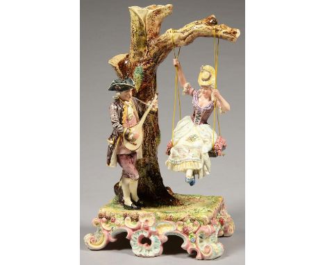 AN EICHLER, ROYAL DUX GLAZED EARTHENWARE GROUP OF LOVERS, THE LADY ON A SWING SERENADED BY A BEAU PLAYING THE MANDOLIN, ON RE