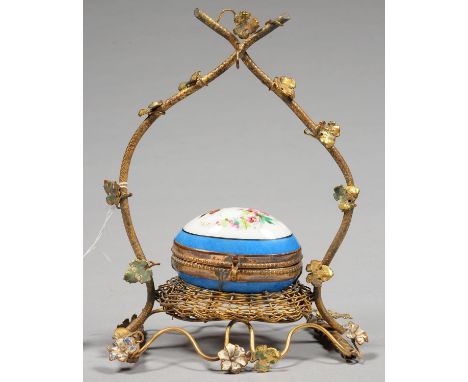 A PALAIS ROYALE GILTMETAL RUSTIC WATCH STAND SET WITH AN OVAL PORCELAIN TRINKET BOX OIN THE FORM OF AN EGG IN A NEST, PAINTED