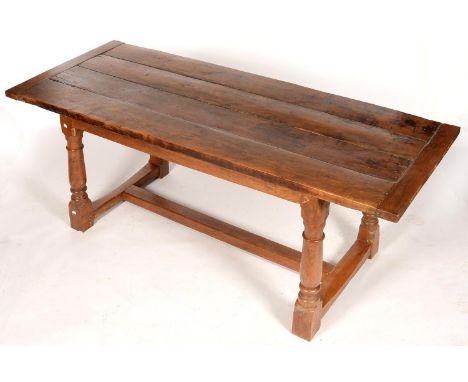 AN OAK REFECTORY TABLE, THE BOARDED TOP WITH CLEATED ENDS ABOVE PLAIN FRIEZE, ON RING TURNED BALUSTER LEGS UNITED BY STRETCHE