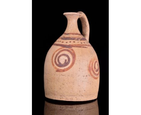 Circa 1400-1100 BCAn early pottery oinochoe finely formed with a slender neck, flaring rim and strap handle, the body with th