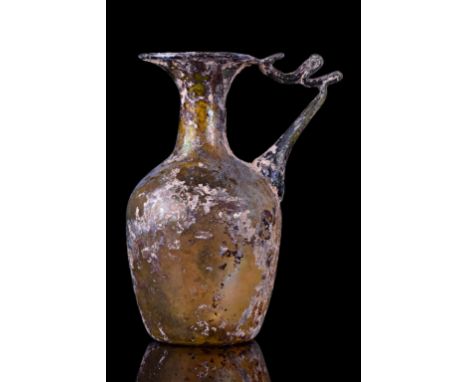 Circa 3rd Century ADThis glass pitcher has an ovoid blown body on a circular, slightly concave base. The elaborate handle fea