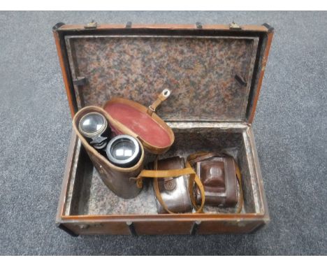 A miniature vintage travelling trunk containing leather cased military field glasses and two leather cased cameras 
