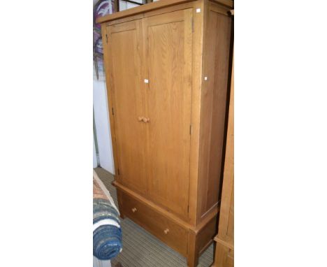 A modern two door light oak wardrobe over a large single drawer