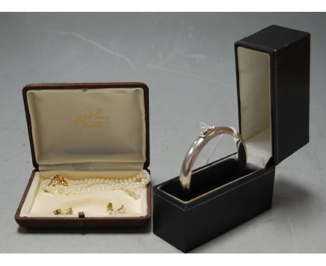 A continental white metal bangle in fitted leather case, together with a single strand pearl necklace on 9ct gold clasp, and 