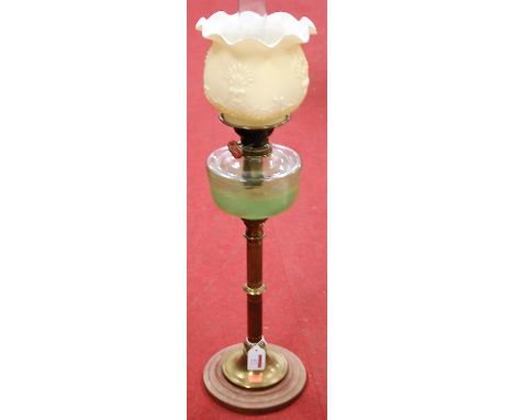 A Victorian oil lamp having a frilled opalescent glass shade above a clear glass reservoir on a brass column and wooden base