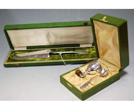 A cased whitemetal two piece christening set comprising eggcup and spoon together with a cased continental white metal cake s