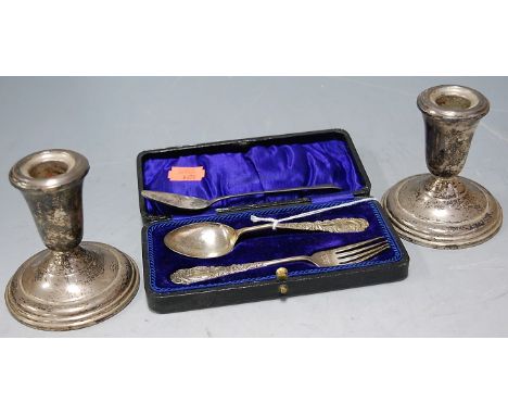 A pair of sterling silver dwarf candlesticks on loaded bases together with a cased silver two-piece christening set, and one 