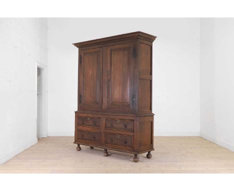 An oak housekeeper's cupboard, early 18th century and later, with a pair of fielded panelled doors above an arrangement of dr