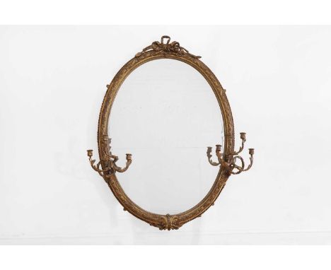 A large carved giltwood and gesso girandole mirror, 19th century, of oval shape with a tied-ribbon crest and foliate detail, 