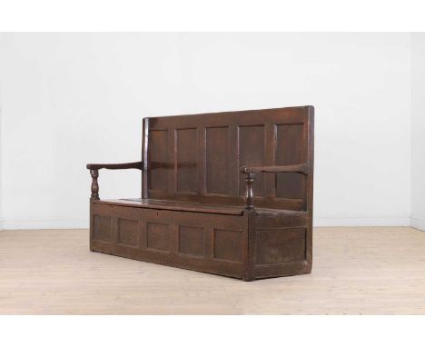 A panelled oak settle, first half of the 18th century, the high back above a plank seat and a box base, 193cm wide 61cm deep 