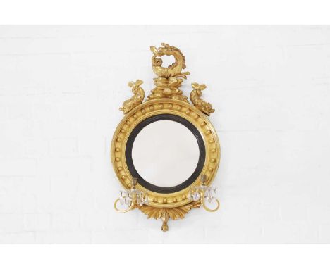 A Regency giltwood convex mirror, early 19th century, the circular frame with a seahorse surmount and a pair of candle sconce