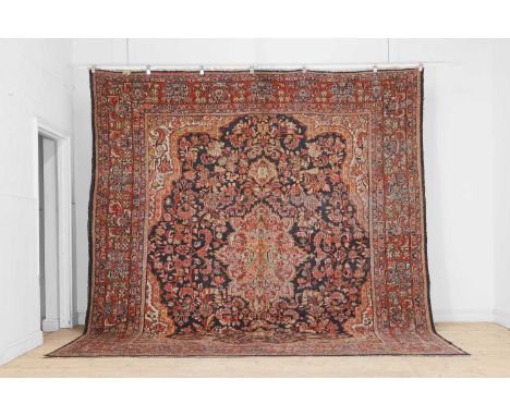A Persian wool carpet, 20th century, the indigo field woven with a central pendant and all-over foliate decoration, within a 